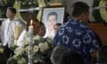 People standing next to flowers, candles and a large photographic portrait of Alejandro Arcos Catalán