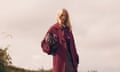 A female model wearing a burgundy coat in countryside setting