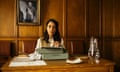 She sits at a typewriter in a wood-panelled office, looking contemplative