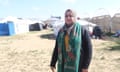 A woman stands in a refugee camp