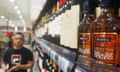 A man (out of focus) walks past bottles of Martell-branded brandy on a supermarket shelf