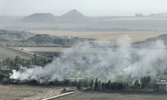 An aerial view of smoke rising over a small rural settlement.