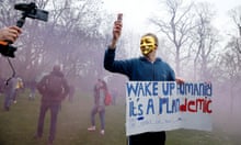 A protester with a gold Anonymous/Guy Fawkes mask and carrying a flare poses holding a sign calling for people to 'wake up'