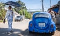 A woman with a parasol walks past a VW Beetle parked in residential neighbourhood of Addis Ababa, Ethiopia