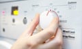 Woman Selecting Cooler Temperature On Washing Machine To Save Energy