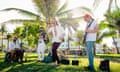 Band performing on grass area of Miami Beach, with palm trees in the background