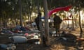 A solider stands among debris from tents amid trees