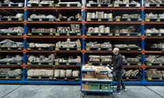 A man pushes a trolley by high shelves of stone objects