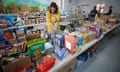 A woman in a yellow cardigan looks down at a table filled with boxed food goods.